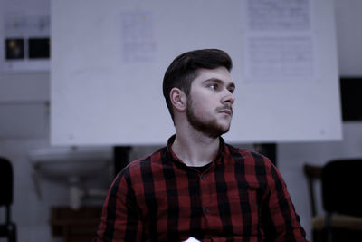 Thoughtful young man standing against wall