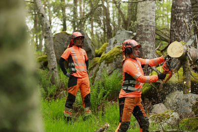 Female lumberjacks cutting log in forest