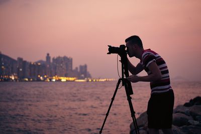 Man photographing against sky during sunset