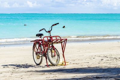 Bicycle parked at beach against sky