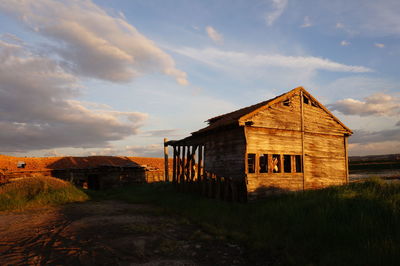 House on field against cloudy sky