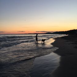 Silhouette people on beach against sky during sunset