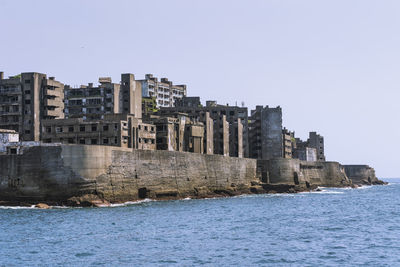 Buildings by sea against clear sky