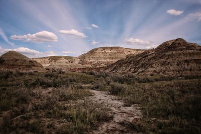 Scenic view of badland rock formations against sky with cloud streaks