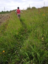 Rear view of woman walking on field