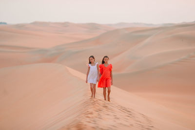 Rear view of couple walking on sand dune