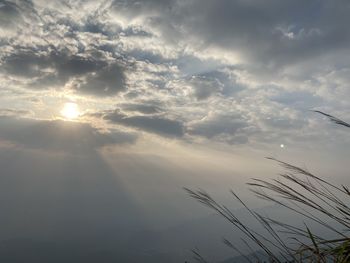 Low angle view of sunlight streaming through clouds