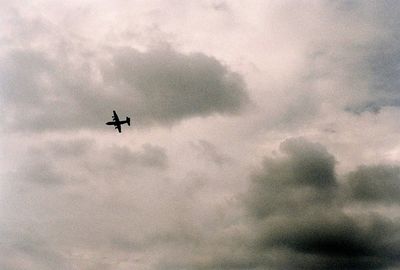 Low angle view of airplane flying against cloudy sky