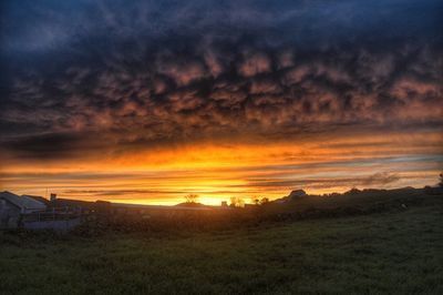 Scenic view of dramatic sky over field during sunset