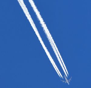 Low angle view of airplane flying against clear blue sky