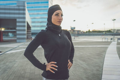 Beautiful woman wearing hijab standing against building during sunrise