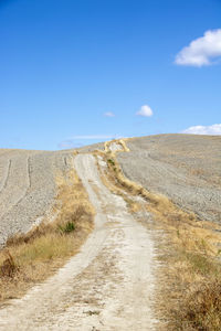 Road passing through landscape against blue sky