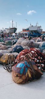 Stack of fishing net at harbor against sky