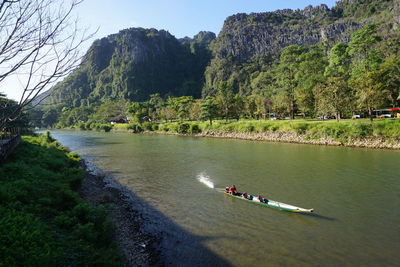 People on boat in lake against mountain