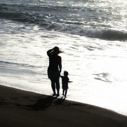 Full length of father and daughter standing on beach