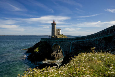 Lighthouse by sea against sky