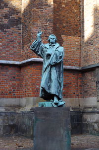 Statue of buddha against brick wall