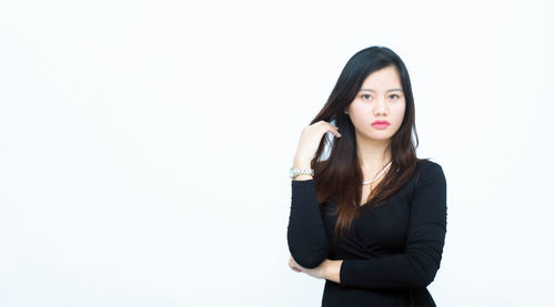 Portrait of young woman standing against white background