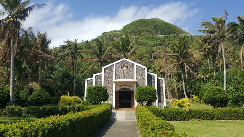 Church amidst plants and trees in garden against sky