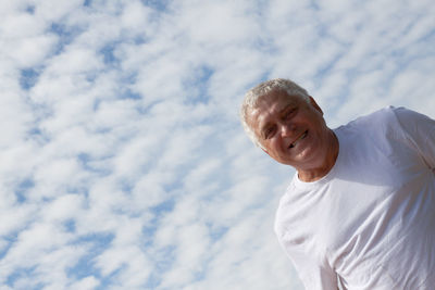 Low angle portrait of mature man against cloudy sky