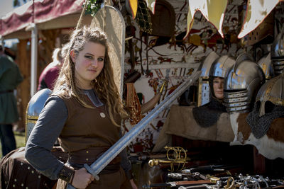 Portrait of confident young woman holding artificial sword