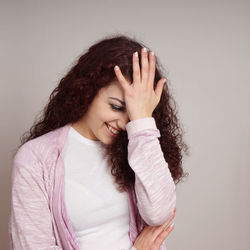 Smiling young woman standing against wall