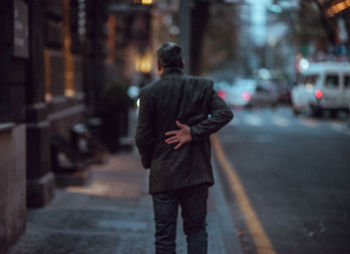 Rear view of man with umbrella walking on street