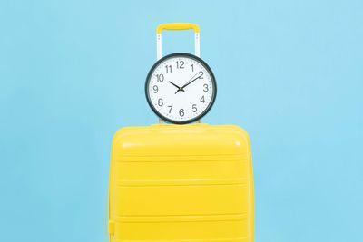 Close-up of yellow clock against blue background