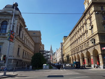 City street by buildings against blue sky