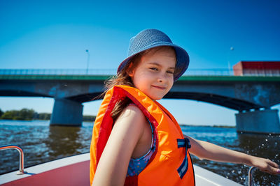 Portrait of smiling girl wearing life jacket standing in boat