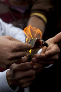 Cropped hands of people burning paper