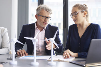 Colleagues discussing while sitting at office desk