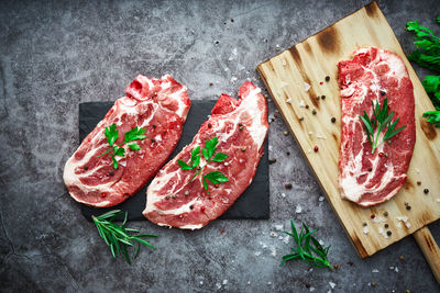 Raw beef steak with tomato, garlic, pepper, salt and rosemary on frying pan on a dark background.