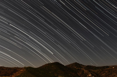 Scenic view of star trails against sky at night.