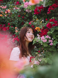 Portrait of young woman standing by plants