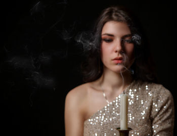 Portrait of beautiful young woman over black background