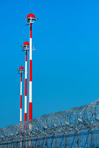 Low angle view of lighthouse by building against clear blue sky