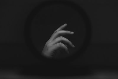 Black and white photo of a hand reflected in a compact mirror