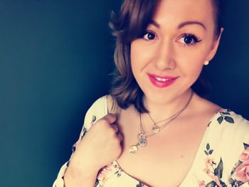 Portrait of smiling young woman against gray background