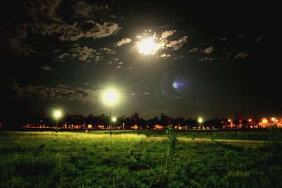 Scenic view of illuminated field against sky at night