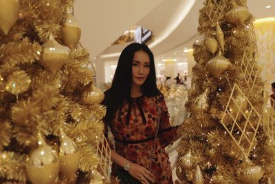 Portrait of woman standing amidst christmas trees