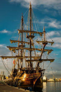 Sailboat moored at harbor against sky