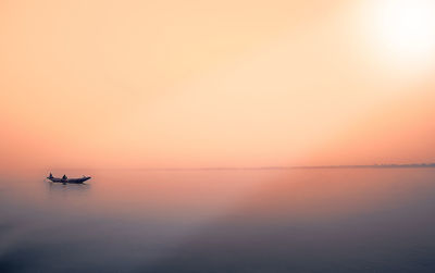 Boat sailing in sea at sunset