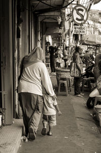 Rear view of people walking on street in city