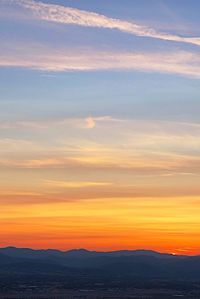 Scenic view of dramatic sky over silhouette landscape during sunset