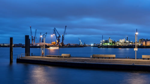 Cranes at harbor against sky at night