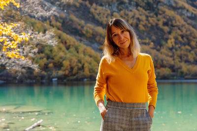 Portrait of young woman standing against lake