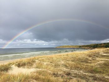 Scenic view of rainbow over sea against sky