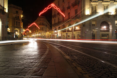 Illuminated light trails on street amidst buildings at night