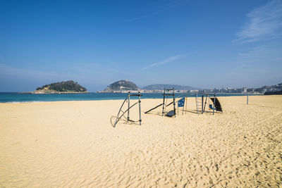 Lounge chairs on beach against blue sky